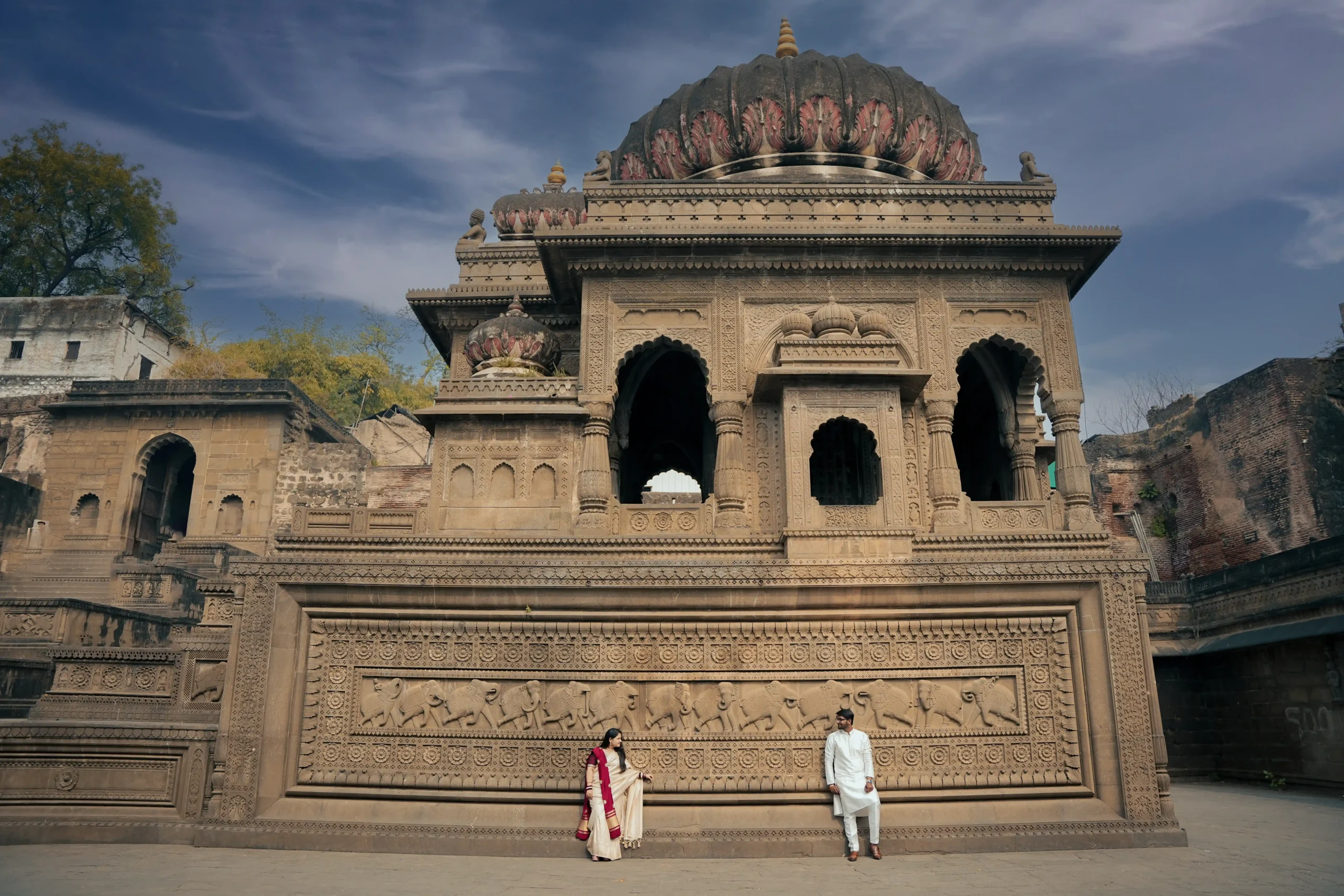 Couple standing in front of an intricately carved heritage temple, representing royal destination wedding venues in India.